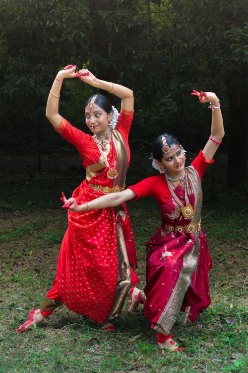 Free Two women perform classical Indian dance in vibrant costumes and jewelry outdoors. Stock Photo