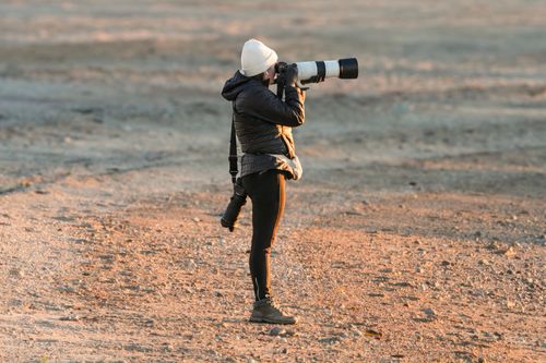 Free Photographer with telephoto lens during golden hour on rugged terrain. Stock Photo