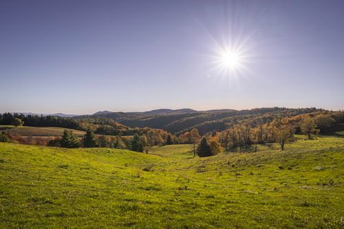 Free Vibrant autumn landscape with sunlit green hills and blue sky, capturing the essence of fall beauty. Stock Photo