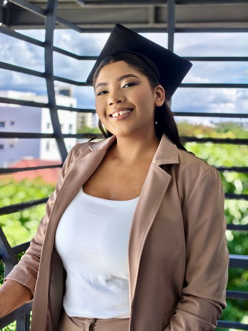 Free Smiling graduate in formal attire posing outdoors against a scenic backdrop, celebrating achievement. Stock Photo