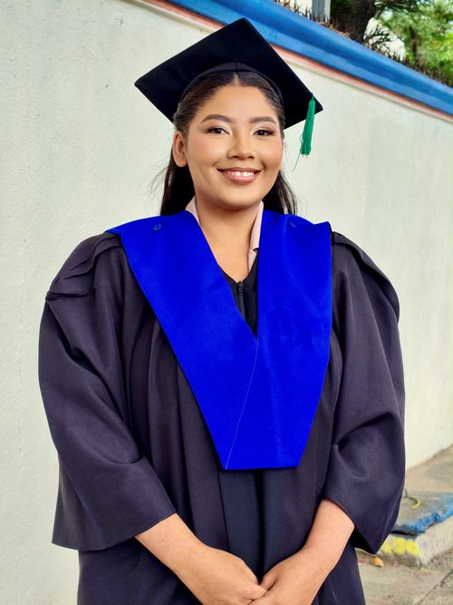 Free Confident young woman celebrating graduation in traditional cap and gown. Stock Photo