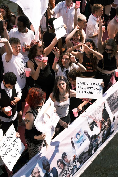 Free Joyful crowd at Amsterdam Pride Parade waving and holding signs celebrating diversity and freedom. Stock Photo