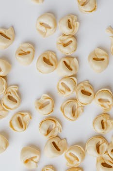 Top view of uncooked tortellini pasta scattered across a white surface.