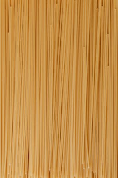 A detailed close-up of raw spaghetti noodles neatly aligned, showcasing their texture and natural color.