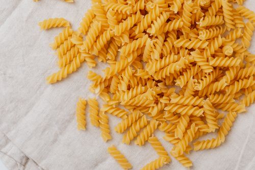 Free Close-up of raw fusilli pasta spirals on a beige linen cloth, perfect for food blogging. Stock Photo