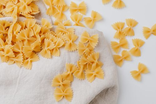 Free A minimalist image showcasing uncooked farfalle pasta scattered on a linen cloth, perfect for culinary themes. Stock Photo
