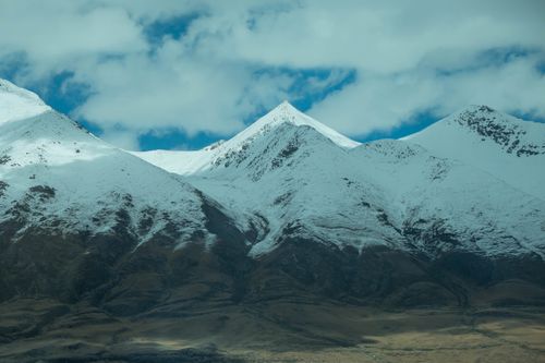 Free Stunning snow-capped mountains with clear blue sky and soft clouds. Stock Photo
