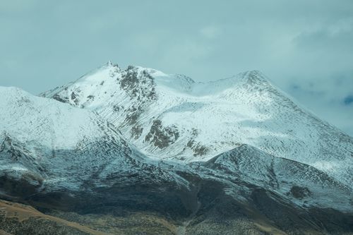 Free Stunning view of snow-covered mountain peaks under a cloudy sky, perfect for winter themes. Stock Photo
