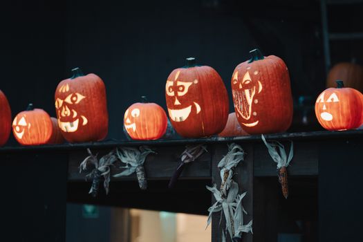 Row of creatively carved jack-o'-lantern pumpkins, perfect for Halloween decoration at night.