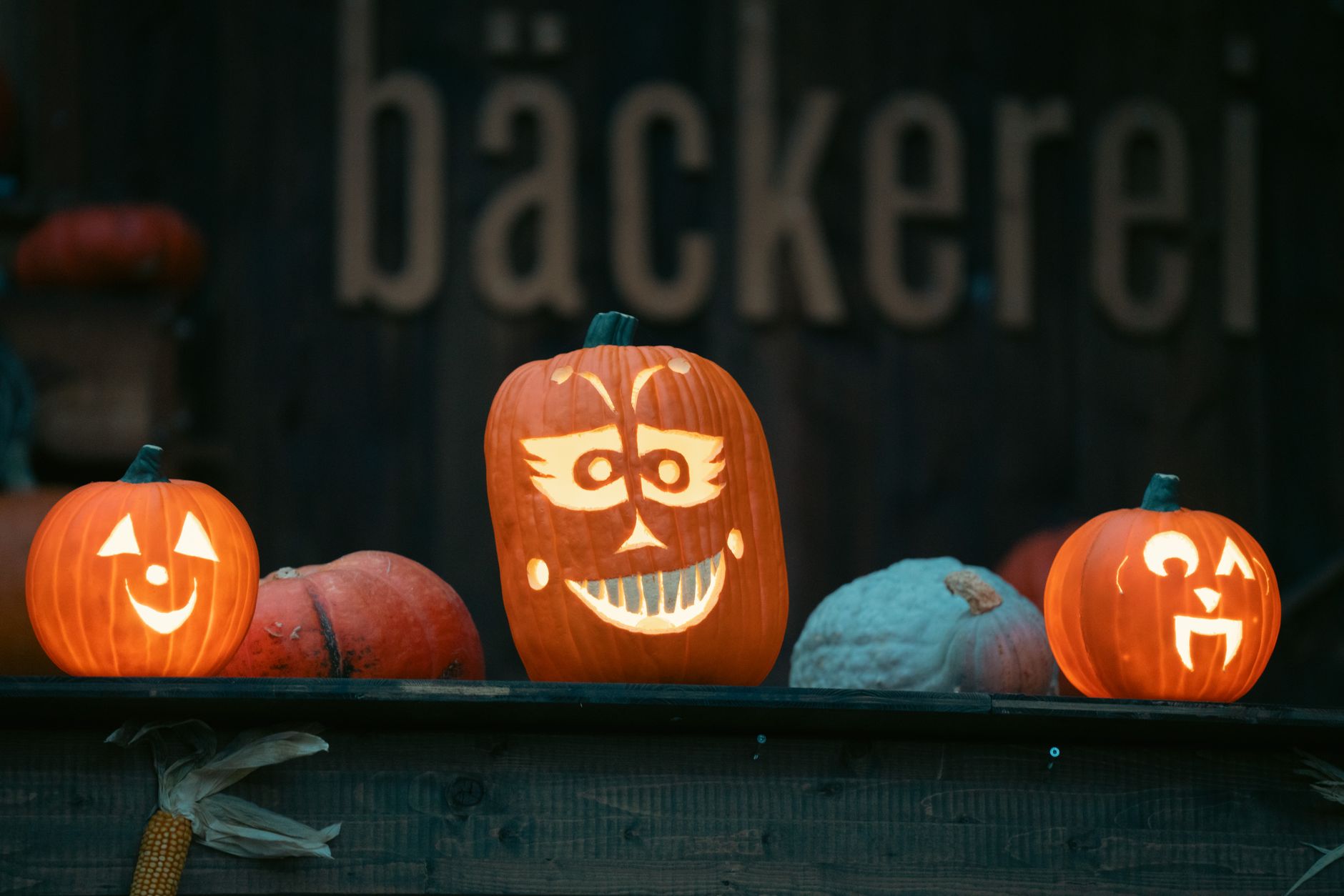 Illuminated jack-o'-lantern pumpkins on a bakery counter during Halloween night.