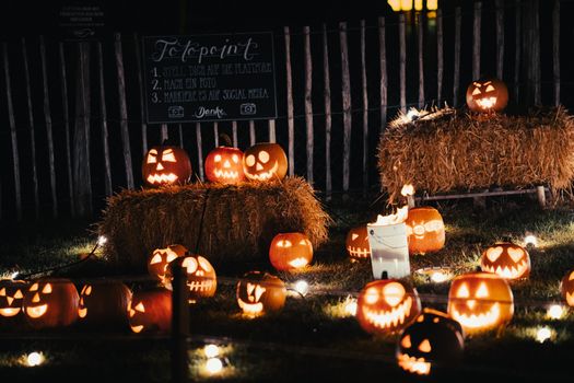 A festive Halloween scene featuring glowing jack-o'-lanterns on hay bales outdoors at night.