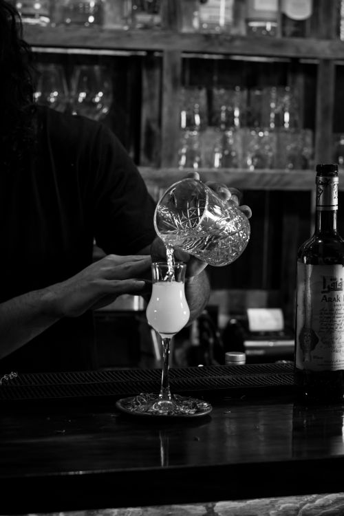 Free Black and white photo of a bartender serving absinthe in a cozy bar. Stock Photo