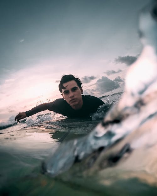 Man in Black Tank Top Swimming on Water