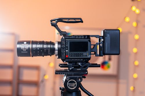 Free High-end cinema camera on a tripod in a studio with blurred bokeh lights backdrop. Stock Photo