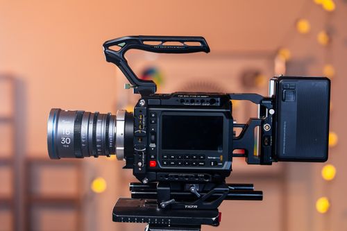Free Side view of a professional cinema camera setup on a tripod, ideal for film production indoors. Stock Photo
