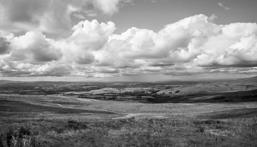 Free Black and white landscape of rolling hills under a dramatic cloudy sky. Stock Photo