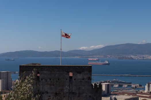 Gibraltar's fortified walls with a flag and stunning ocean and mountain views.