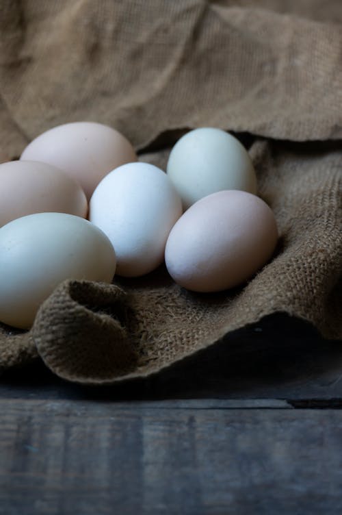 Uncooked chicken eggs placed on brown rag on table at home in village