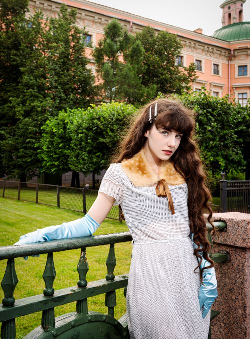 Free A woman in a vintage dress stands elegantly in a garden setting, exuding timeless beauty. Stock Photo