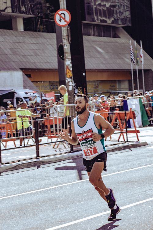 Free Focused athlete competing in a city marathon on a sunny day with cheering crowd. Stock Photo