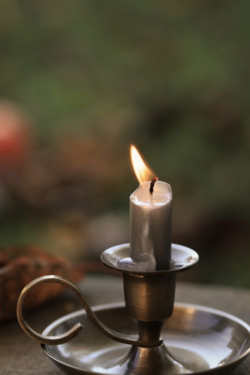 Free A cozy candle flame glowing in a vintage holder, perfect for autumn ambiance. Stock Photo