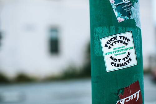 Free Green pillar with sticker with provocative lettering fuck system not climate on street in city Stock Photo