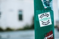 Green pillar with sticker with provocative lettering fuck system not climate on street in city