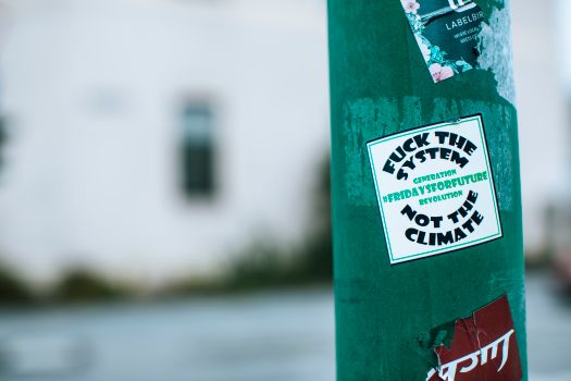 Green pillar with sticker with provocative lettering fuck system not climate on street in city