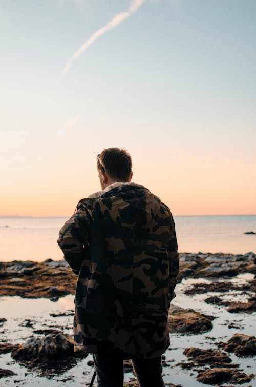 Male traveler standing on stony shore