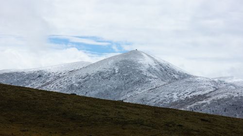 Free Serene snowy mountains and grassland under a bright cloudy sky. Stock Photo
