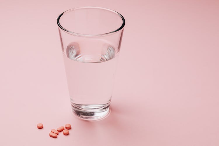 Photo Of Glass Of Water Beside Capsules