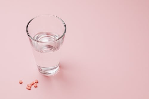 Photo Of Glass Of Water Beside Capsules
