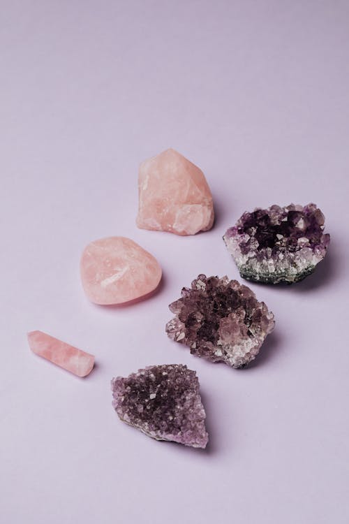 Top view of shiny rose quartz and geode amethyst semiprecious stones placed on gray surface in jewelry shop