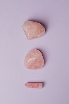 在柔软的紫色背景上，一组由三块玫瑰石英石构成的简约组合，展现了其自然之美