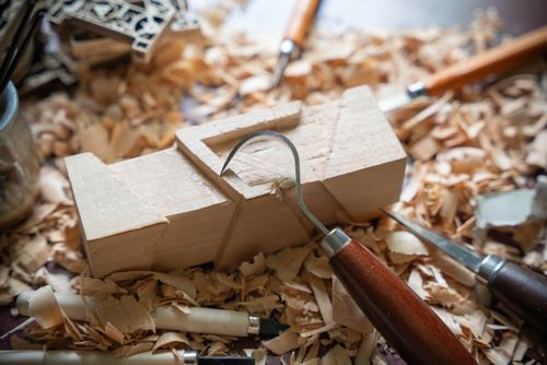 Free A close-up of woodworking tools and carved wood in a workshop setting, highlighting craftsmanship. Stock Photo