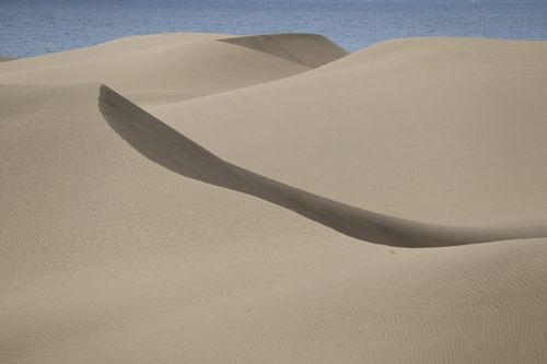 Free Tranquil coastal sand dunes meet the ocean under clear skies in Spain. Stock Photo