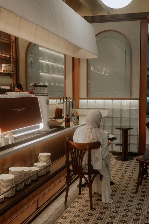 Free Warm interior shot of a modern café with a person seated, capturing the serene ambiance. Stock Photo