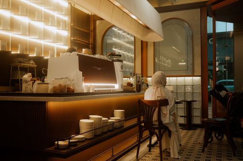 Free Warm interior of a stylish modern café with a single seated adult, showcasing ambient lighting. Stock Photo