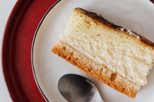 Free Closeup of yummy piece of cake with chocolate cream served on white plate with tea spoon placed on red plate Stock Photo