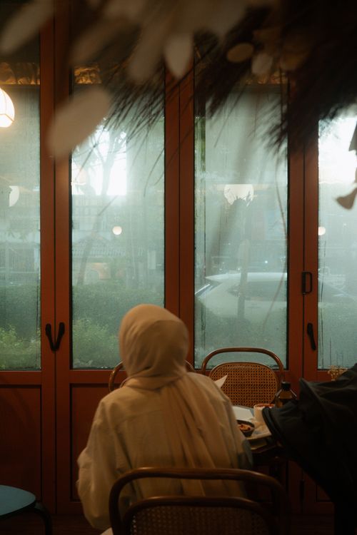 Free A serene moment inside a cozy cafe with a person enjoying the rainy view outside. Stock Photo