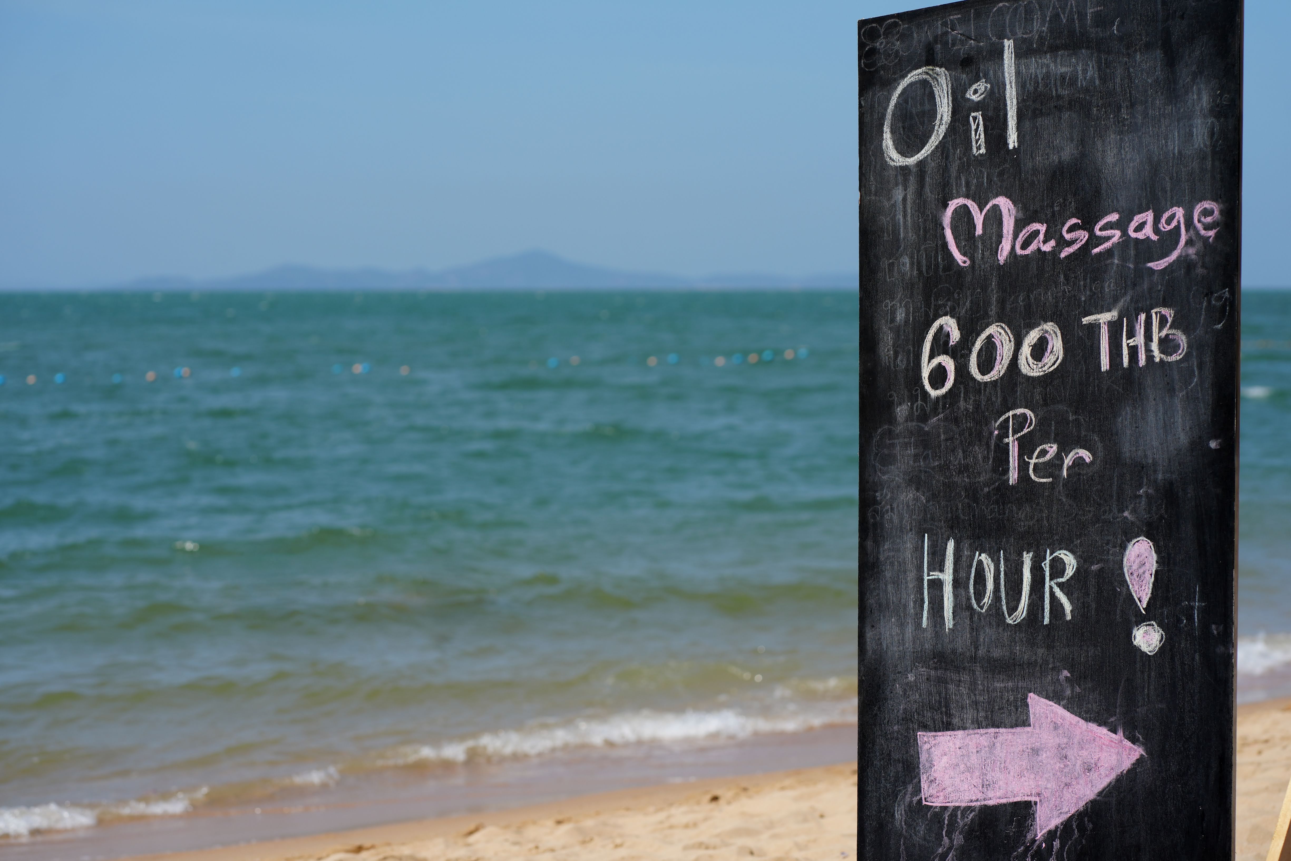 Chalkboard sign for beachfront massage in Pattaya City, Thailand.