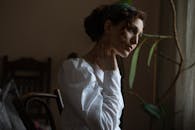 在室内昏暗的灯光下拍摄的一位卷发女子的肖像，以沉思姿势