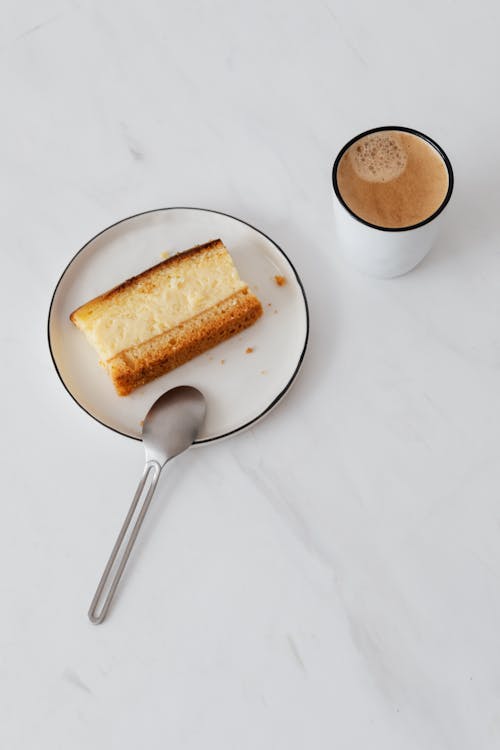 Top view of baked sweet piece of pie on plate near cup of hot coffee on white marble table