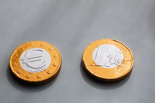 Close-up of chocolate coins designed as Euros, wrapped in metallic foil on gray background.