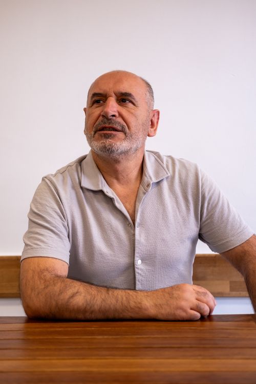 Free A contemplative mature man seated indoors against a neutral background. Stock Photo