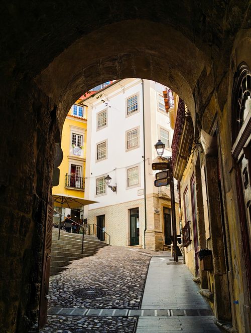 Free Historic European street view through an archway with cobblestones and quaint buildings. Stock Photo