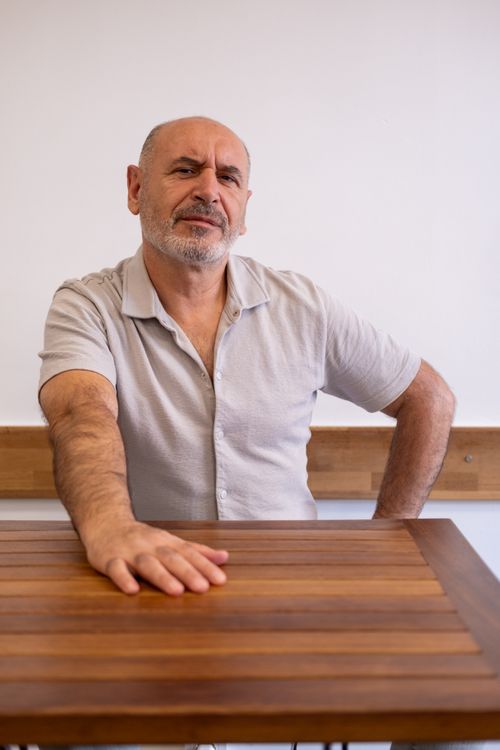 Free Casual portrait of a confident middle-aged man sitting at a wooden table indoors. Stock Photo