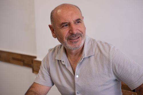 Free Portrait of a smiling middle-aged man in a light shirt sitting indoors in Izmir, Türkiye. Stock Photo
