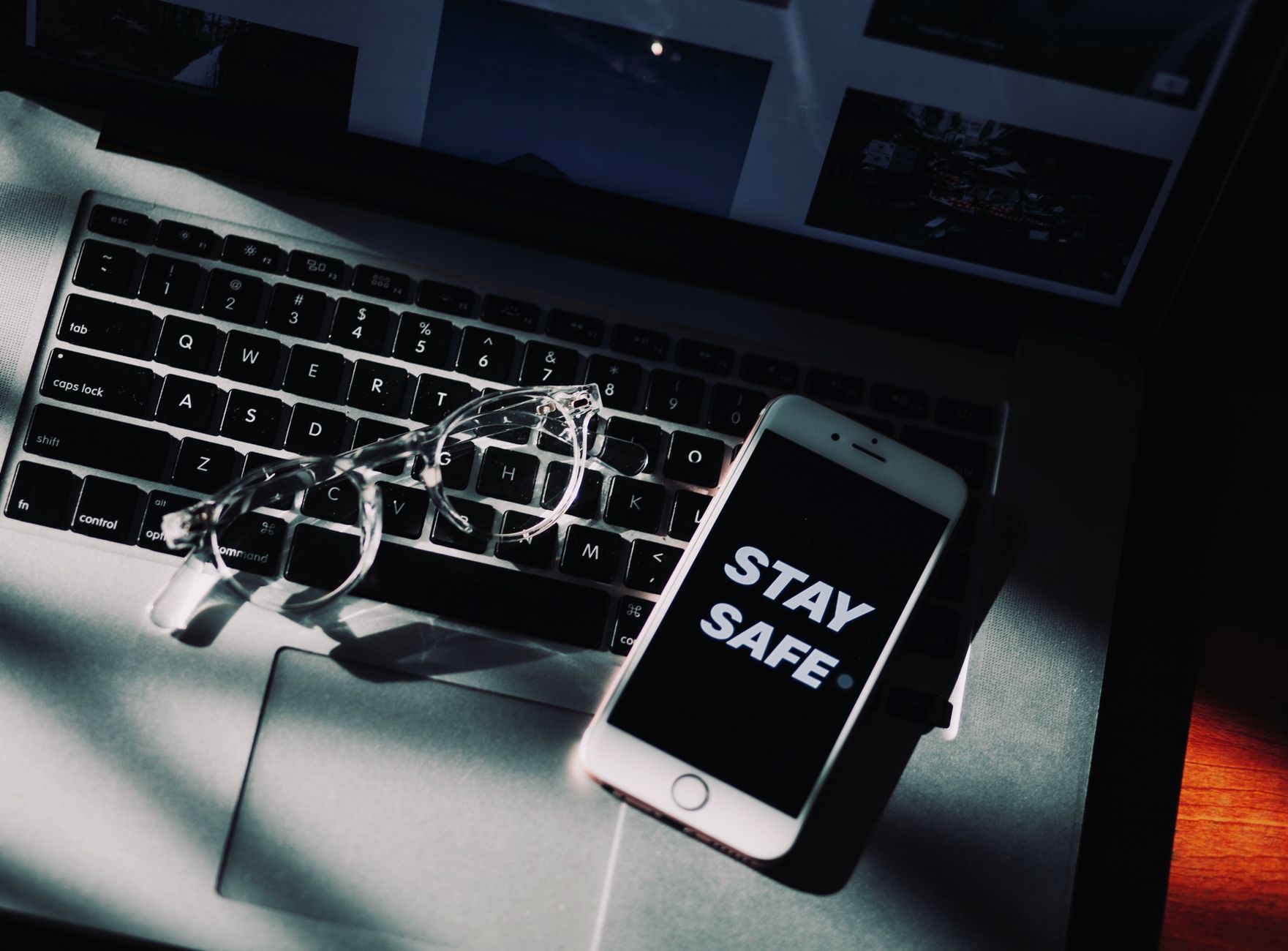 Eyeglasses and smartphone display 'Stay Safe' on laptop, emphasizing remote work.