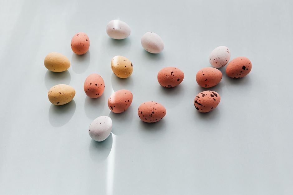 Pastel-colored Easter eggs with dotted patterns arranged on a light background, creating a minimalistic festive scene.